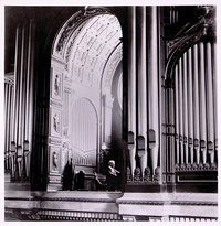 Photographie noir et blanc montrant un homme jouant sur un grand orgue d'église.