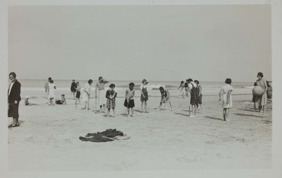 Photographie noir et blanc montrant des jeunes filles jouant au croquet et au ballon sur la plage.