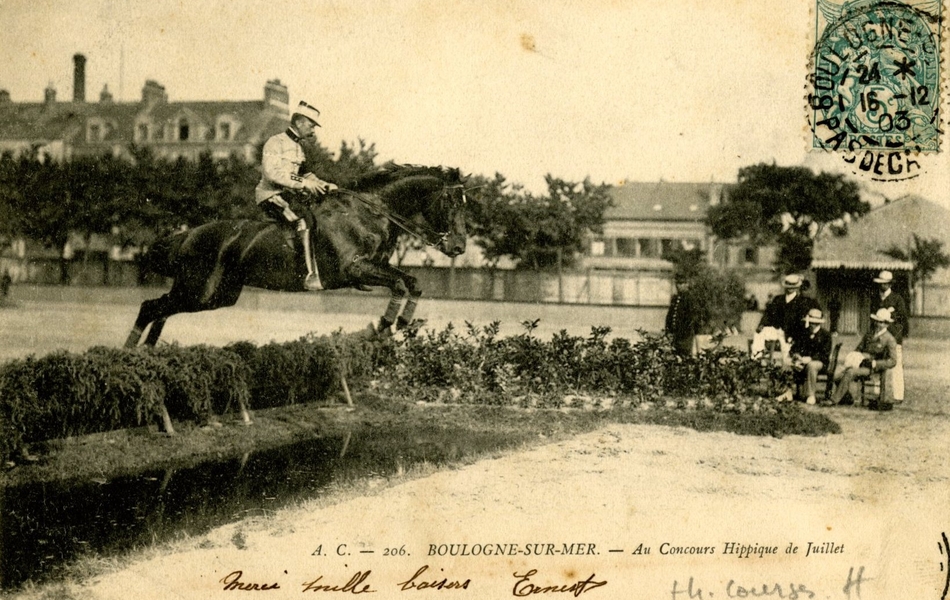 Carte postale noir et blanc où l’on voit un cheval monté par un cavalier sautant un obstacle, devant une petite assistance.