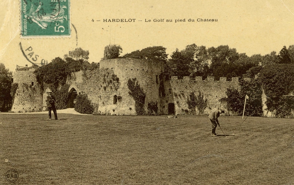 Carte postale noir et blanc d’un green occupé par deux hommes au pied d’un château médiéval.