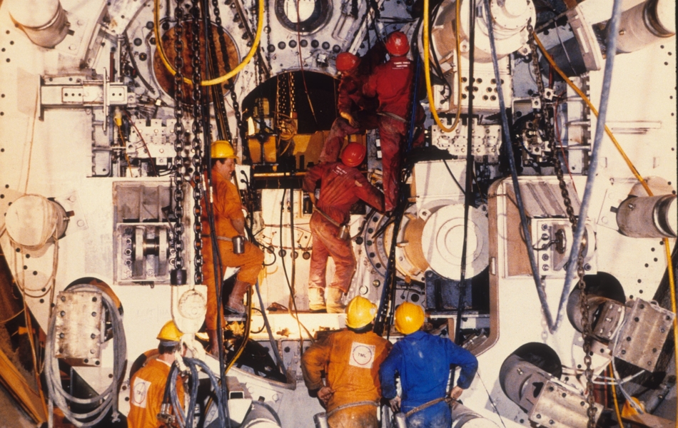 Photographie couleur montrant des ouvriers et des machines.