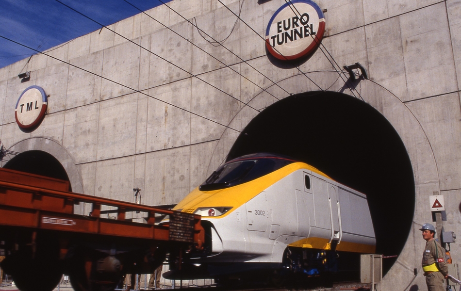Photographie couleur montrant un train à grande vitesse tracté, sortant d'un tunnel au-dessus duquel on voit le logo "Eurotunnel".