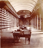 Photographie sepia montrant une grande salle de bibliothèque avec des tables au centre.