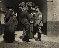 Photographie noir et blanc montrant un groupe de personnes discutant debout dansd une cour.