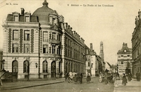 Carte postale noir et blanc montrant un bâtiment au croisement du rue.