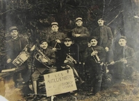 Photographie noir et blanc montrant un petit groupe de musicien en-dessous duquel est posée une pancarte sur laquelle on lit : "Les anti-cafaristes".