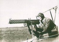 Photographie noir et blanc montrant un aviateur allemand ternant une mitrailleuse à bord d'un avion.