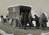 Photographie noir et blanc montrant un groupe de femmes chargeant un brancard dans une ambulance.