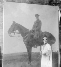 Le peintre Jules Joëts en uniforme, surmontée d'une blouse blanche, posant devant le portrait équestre de Sir Douglas Haig.