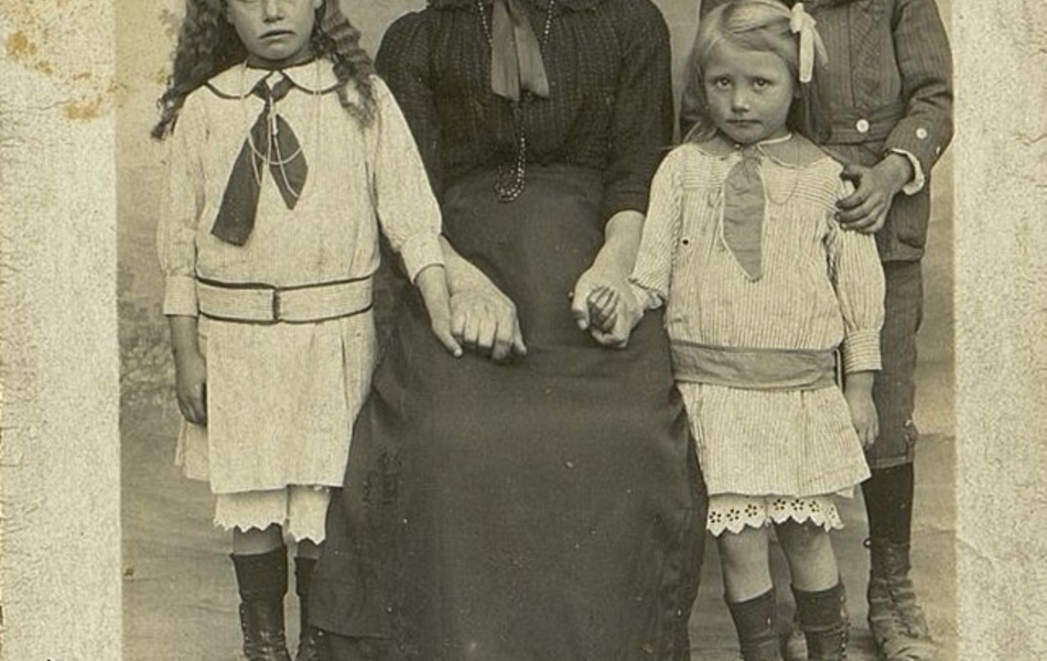 Photographie noir et blanc montrant une femme assise entourée de ses trois enfants.