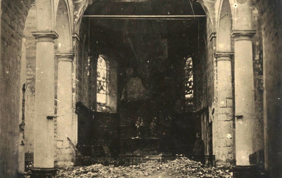 Photographie noir et blanc montrant une église dévastée. Au sol repose sa cloche.
