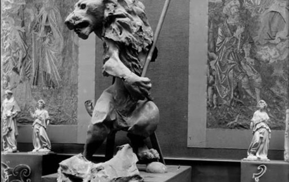 Photographie noir et blanc montrant une statue de lion exposée au milieu d'autres œuvres d'art.