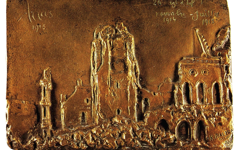 Photographie couleur montrant une plaque de cuivre sur laquelle est gravée les ruines de bâtiments. 