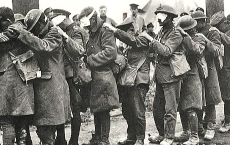 Photographie noir et blanc montrant des hommes aux yeux bandés en file indienne.