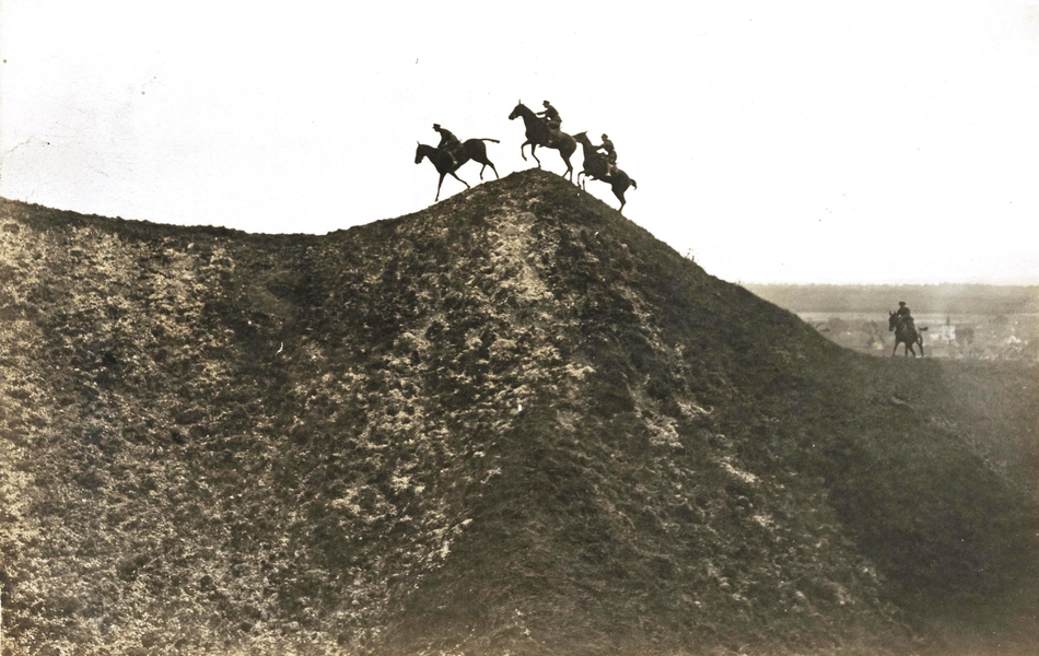 Photographie noir et blanc montrant trois cavaliers galopant en haut d'une colline.