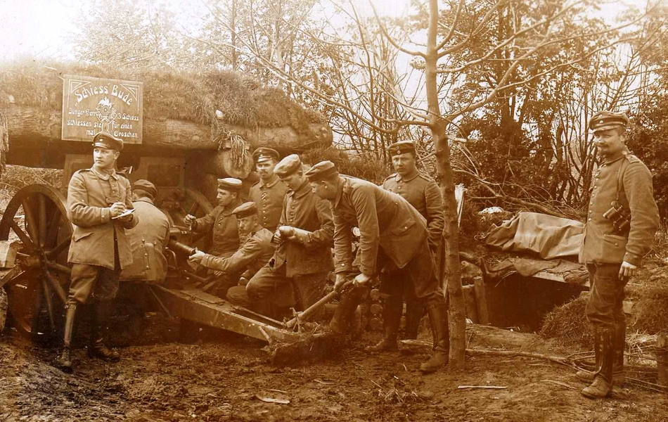 Photographie sepia montrant des hommes en train de charger un canon d'artillerie devant des abris.