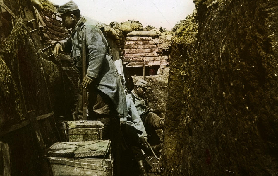 Photographie couleur montrant un soldat debout dans une tranchée.