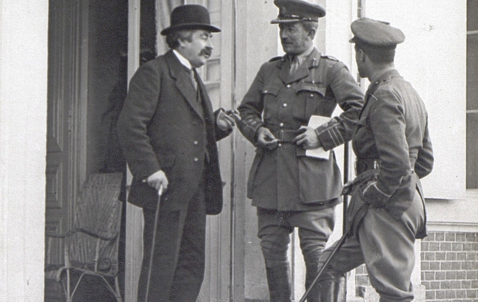 Photographie noir et blanc montrant trois hommes sur le perron d'un château, dont deux militaires et un civil.