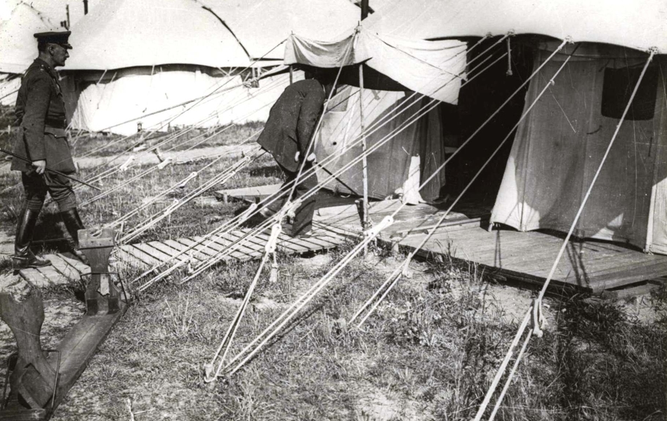 Photographie noir et blanc montrant un homme pénétrant dans une tente.