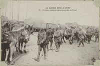Carte postale noir et blanc montrant des soldats indiens souriant décharger des baages de leurs montures.