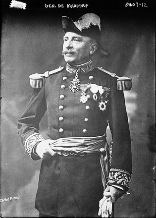Photographie noir et blanc montrant un homme tourné de trois-quart, vêtu d'un costume militaire décoré de nombreuses insignes et médailles.