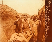Photographie sepia montrant un homme allongé dans une civière, porté par deux autres suivis de quelques soldats dans une tranchée.