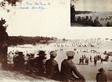 Photographie noir et blanc montrant au premier plan une rangée d'hommes de dos, assis et regardant une plaine occupée par un camp de tentes.