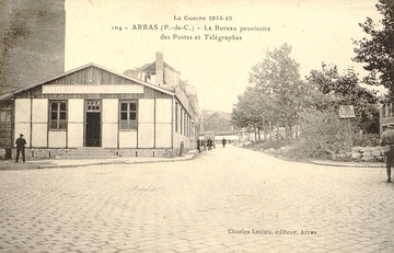 Carte postale noir et blanc montrant un baraquement au coin d'une rue.