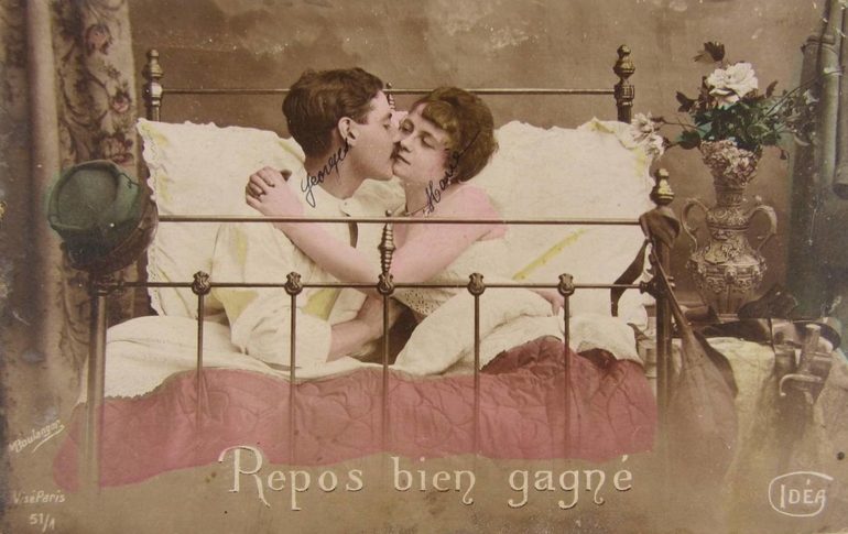 Carte postale couleur montrant un couple enlacé dans un lit.