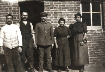 Photographie noir et blanc montrant des civils encadrant un soldat allemand.