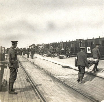 Photographie noir et blanc montrant un groupe de soldats sur un quai de gare, prêts à monter dans un train. On remarque que certains se trouvent sur des civières.