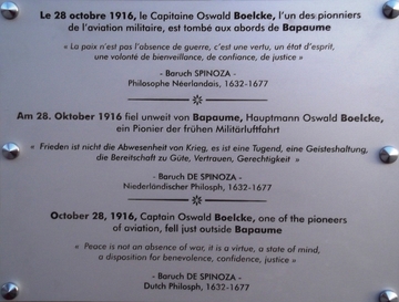 Texte gravé sur lequel on lit en français, allemand et anglais le texte suivant : "Le 28 octobre 1916, le capitaine Oswald Boelcke, l'un des pionniers de l'aviation militaire, est tombé aux abords de Bapaume. La paix n'est pas l'absence de la guerre, c'est une vertu, un état d'esprit, une volonté de bienveillance, de confiance, de justice. Baruch Spinoza, philosophe néerlandais, 1632-1677".