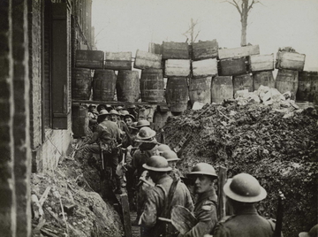 Photographie noir et blanc montrant des soldats dans une tranchée protégée par des tonneaux.