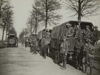 Photographie noir et blanc montrant un convois de camions transportant des soldats.