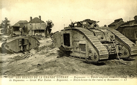 Carte postale. Photographie de 2 chars anglais au premier et second plan. Au fonds, des maisons de briques en ruines.