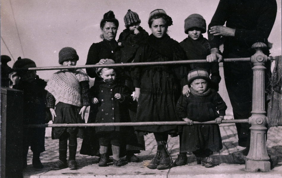 Photographie noir et blanc montrant une famille dont sept enfants d'âges différents alignés le long d'un quai.