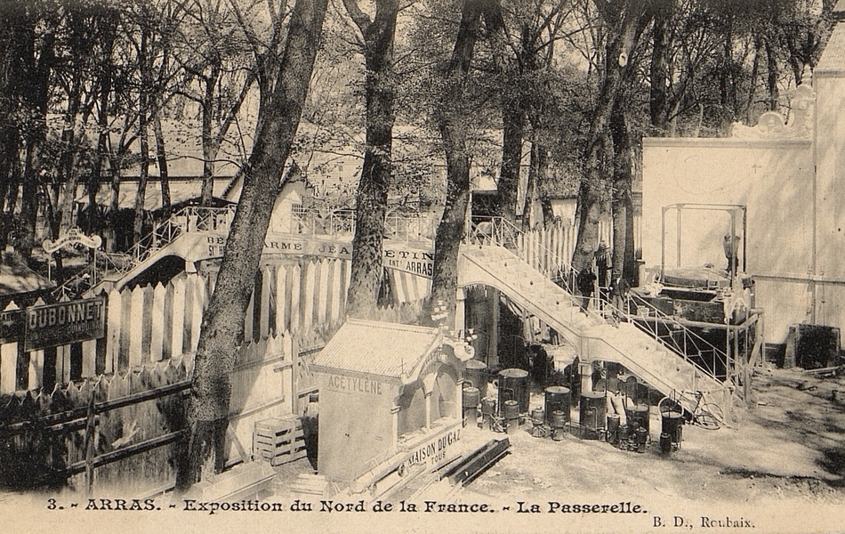 Carte postale noir et blanc montrant une passerelle métallique installée parmi les arbres au-dessus de deux clôtures en bois.