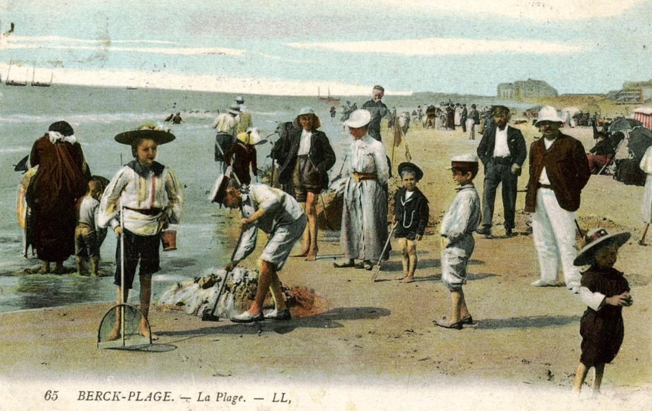 Carte postale couleur d'un bord de plage très fréquenté. On y voit des promeneurs, des enfants jouant dans le sable, des personnes assises dans des transats et des baigneurs