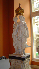 Sculpture en marbre représentant les trois grâces, surmontée d’une urne dorée.