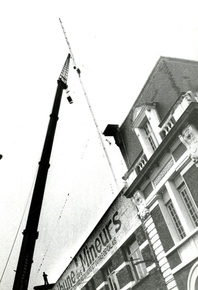 Photographie noir et blanc en contre-plongée montrant le haut d'un bâtiment et une antenne.