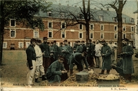 Carte postale couleur montrant des militaires en train d'épucher des pommes de terre autour de bassines dans une cour.