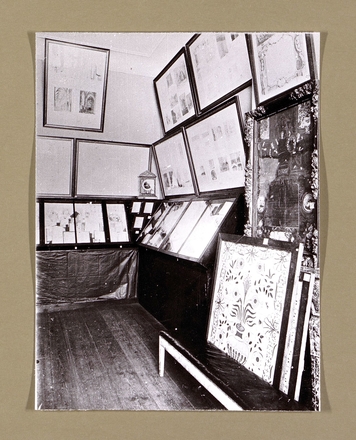 Photogrpahie noir et blanc montrant des manuscrits sous vitrines et des tableaux aux murs.