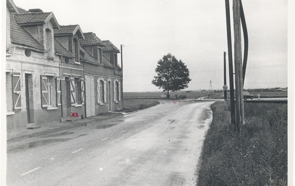 Photographie noire et blanc d'une rue bordée de maisons.