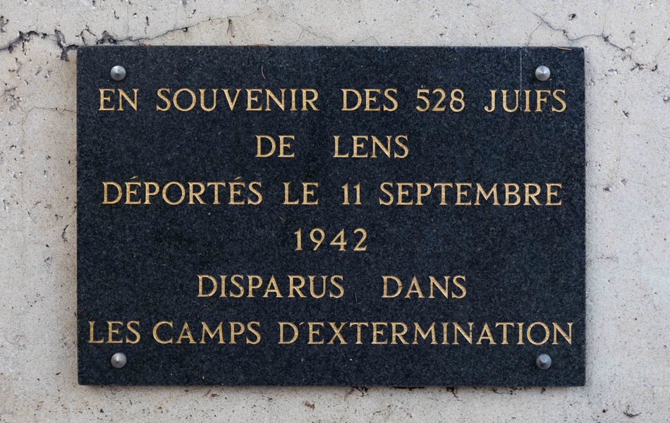 Photographie couleur d'une plaque commémorative sur laquelle on lit : "En souvenir des 528 juifs de Lens déportés le 11 septembre 1942, disparus dans les camps d'extermination".
