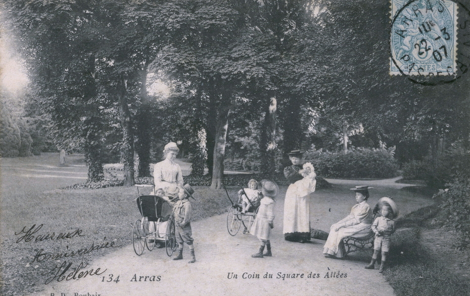 Carte postale noir et blanc montrant deux jeunes femmes entourées de six enfants et bébés dans une allée bordée d'arbres.