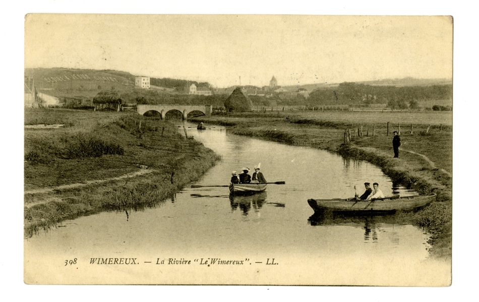 Carte postale en noir et blanc de la rivière le Wimereux et ses berges. Au loin, on aperçoit un pont et les toits d’un village. Trois barques naviguent sur la rivière le Wimereux