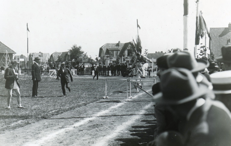 Photographie noir et blanc d'athlètes sautant des obstacles devant une foule de spectateurs.