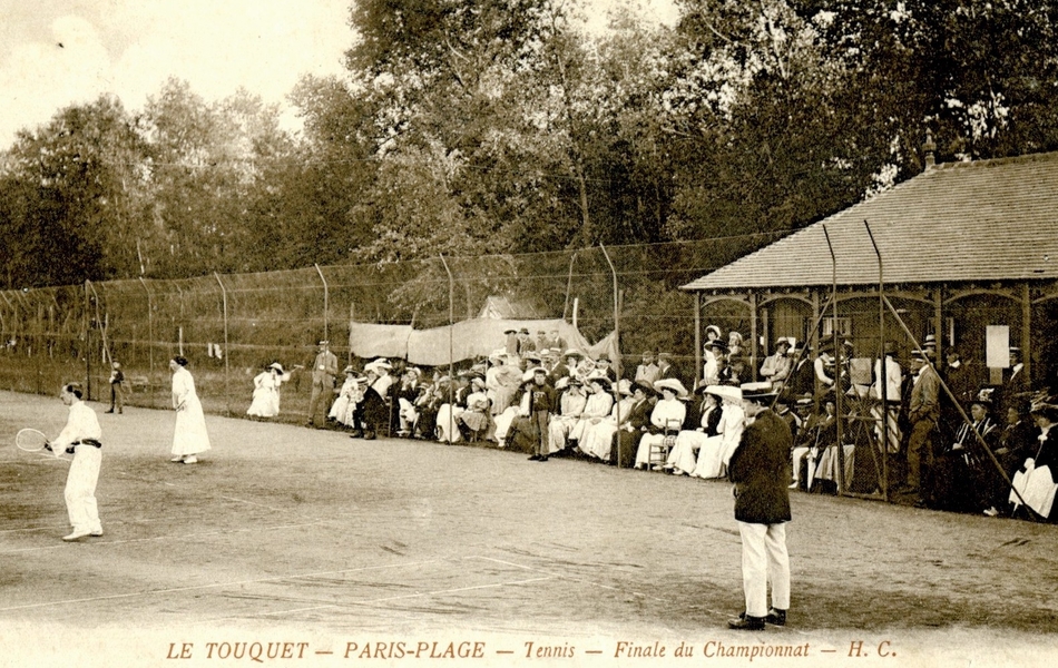 Carte postale noir et blanc montrant une tribune de spectateurs devant un court de tennis.