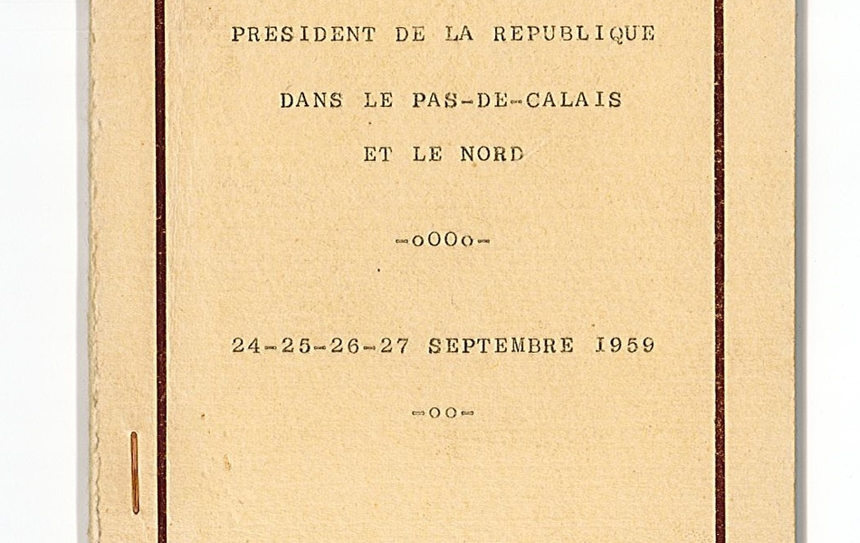 Photographie couleur montrant la couverture d'un petit cahier avec comme marque-page un ruban tricolore. Dessus on lit : "Voyage de Monsieur le général de Gaulle, président de la République, dans le Pas-de-Calais et le Nord. 24-25-26-27 septembre 1959".