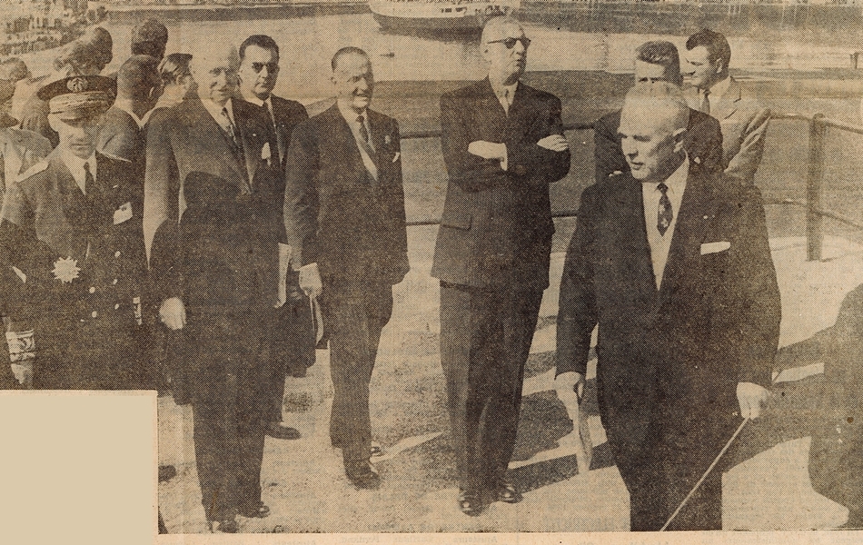 Photographie noir et blanc de presse sur laquelle on voit le général de Gaulle debout au milieu d’un groupe d’officiels, sur un quai.